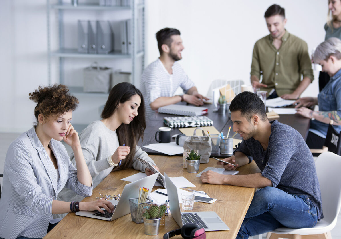 Young diverse female and male coworkers brainstorming ideas for a project by a table at a start-up office