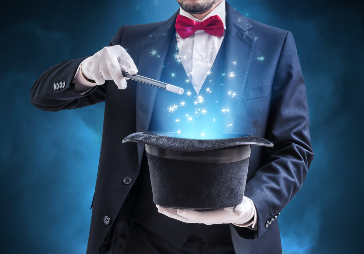 Magician or illusionist is showing magic trick. Blue stage light in background.