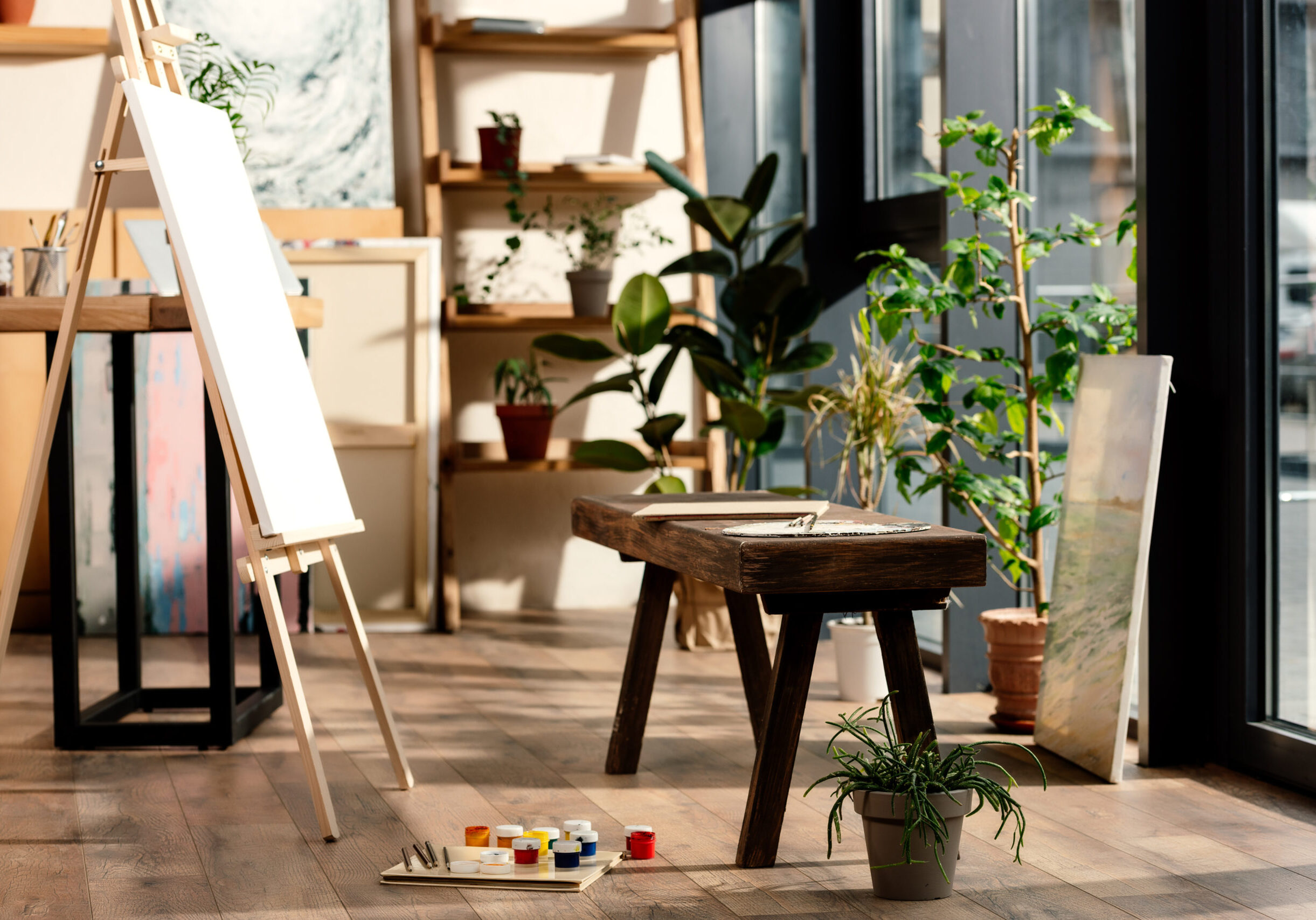 interior of artist studio with painting supplies, potted plants and bench