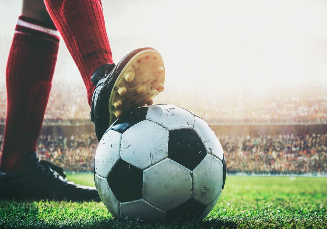 feet of soccer player tread on soccer ball for kick-off in the stadium